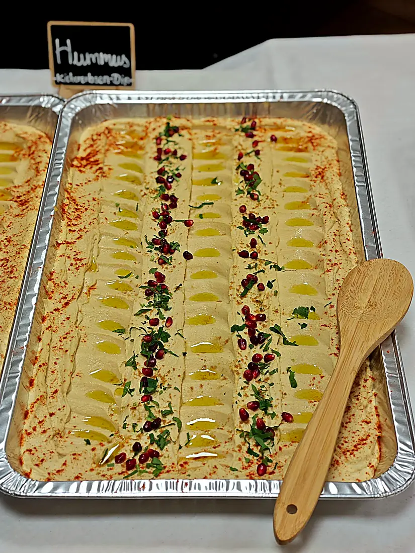 Hummus in großer Schale mit Olivenöl, Granatapfelkernen und Paprika