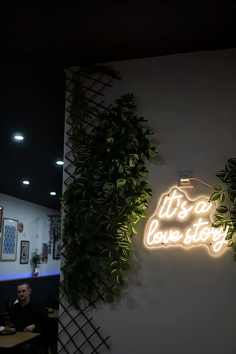 Leuchtschriftzug "it's a love story" an der Wand des Gastraums
